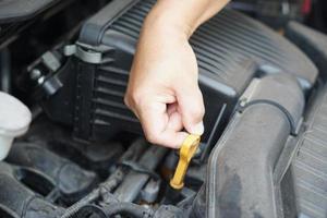 Closeup hand hold yellow scale for fuel measurement level in car engine. Concept, automobile maintenance. Check and repair before driving for safety. Basic diagnose vehicle problems. photo