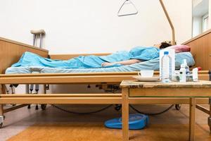 hospital bed with sick person and table at home photo