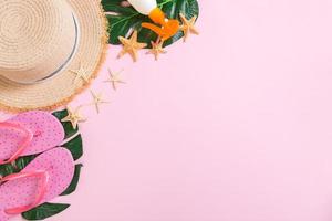 Beach accessories with straw hat, sunscreen bottle and seastar on pink background top view with copy space photo