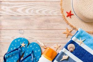 flip flops, straw hat, starfish, sunscreen bottle, body lotion spray on wooden background top view . flat lay summer beach sea accessories background, vaation concept photo