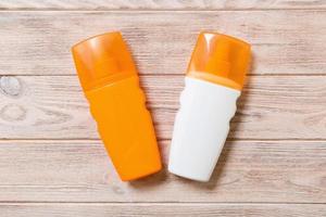 Two Sunscreen bottles on a bright wooden background, top view photo