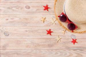 Summer holiday background with straw hat and seashells on wooden background top view with copy space photo