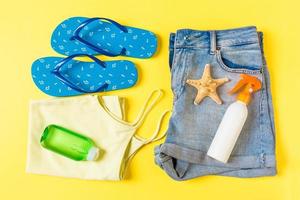 Flat lay composition with Beach accessories on yellow color background. Summer holiday background. Vacation and travel items top view photo