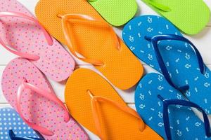 a lot of flip flop colored sandals, summer vacation on wooden background, copy space top view photo