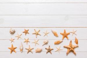 Summertime wooden table with starfish and seashells on a white background top view. Copy space background, summer concept photo