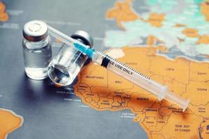 jeringa médica con aguja y bollte con vacuna en el mapa mundial. foto