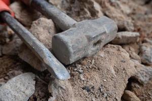 selective focus to stone chisel and hammer on collapsed building rubble, demolished building renovation and evacuation concept, soft focus photo