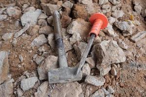 selective focus to stone chisel and hammer on collapsed building rubble, demolished building renovation and evacuation concept, soft focus photo