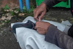 selective focus on sandals that are being repaired by sewing using thread and needles, this work is called in Indonesia a tukang sol sepatu, soft focus photo