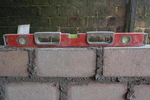 selectively focus on spirit level, also called waterpass or water level. Level to Check Bricklaying Foundation Wall Outdoors. soft focus photo