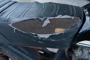 selectivo fokus en el lacerado motocicleta asiento , antiguo negro cuero asiento es dañar , roto cuero. foto