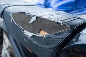 selectivo fokus en el lacerado motocicleta asiento , antiguo negro cuero asiento es dañar , roto cuero. foto