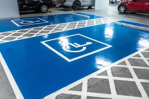 Car parking lot reserved for handicapped driver in supermarket or shopping mall. Car parking space for disabled people. Wheelchair sign paint on parking area. Blue and white handicapped parking lot. photo
