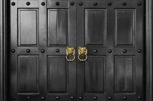 Golden lion head door handle on retro black wooden door photo