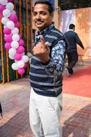 New Delhi, India - December 04 2022 - Unidentified people showing their ink-marked fingers after casting votes in front of polling booth of east Delhi area for MCD local body Elections 2022 photo