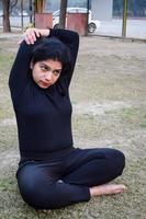 joven india practicando yoga al aire libre en un parque. hermosa chica practica pose básica de yoga. calma y relax, felicidad femenina. posturas básicas de yoga al aire libre foto
