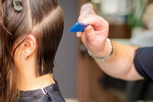 peluquero haciendo Corte de pelo de joven mujer foto