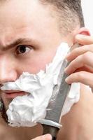 Man shaving beard with knife photo