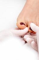Manicure master holds female toenail photo