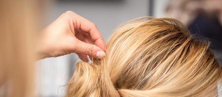 hairdresser makes hairstyle of young woman photo