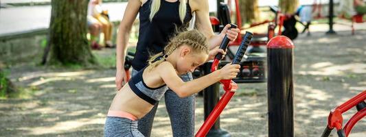 Little girl does exercises on simulator photo