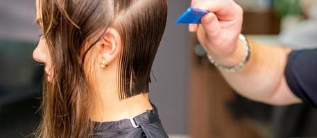 peluquero haciendo Corte de pelo de joven mujer foto