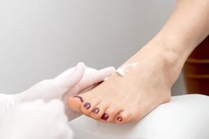 Pedicurist in white gloves massaging cream photo