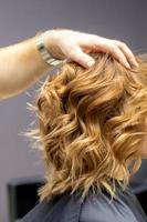 Hairdresser checks curly hairstyle of woman photo