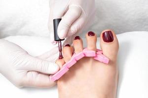 Manicure master is painting female toenails photo