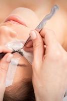 Woman receiving eyelash extensions procedure photo