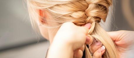 Female hands braiding pigtail to woman photo