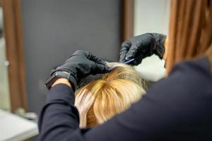 Female hairdresser makes hairstyle for woman photo