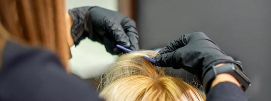 Female hairdresser makes hairstyle for woman photo