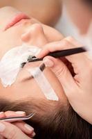 Woman receiving eyelash extensions procedure photo