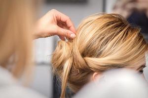 peluquero hace peinado de joven mujer foto