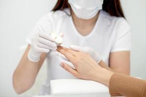 Manicurist applying wax on fingernails photo