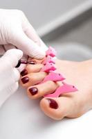 Manicure master is painting female toenails photo