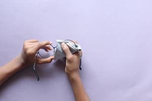 hand cleaning glasses lens with a cloth . photo