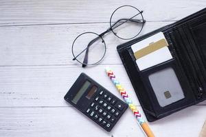 cards in a wallet , calculator and pen on table photo