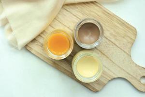 Caramel, chocolate and mango pudding in a glass jar on pink background photo