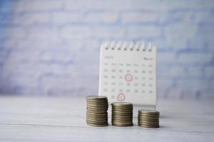 stack of coins and calendar on table photo