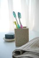 colorful toothbrushes in white mug against a wall photo