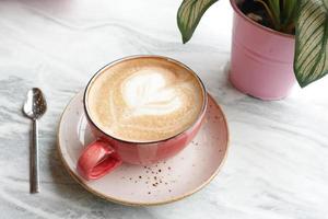 a cup of late coffee with flower shape design on top at cafe photo