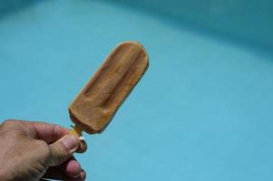 hand holding popsicle on blue background photo