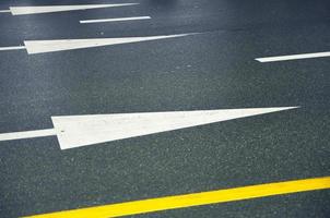 White arrows and yellow lines on a wet asphalt road. photo