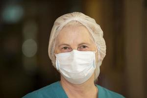 The face of an elderly female doctor or nurse in a medical mask, with kind eyes, close-up. photo