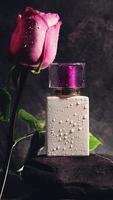 White perfume bottle with purple top and rose with water drops. mockup photo