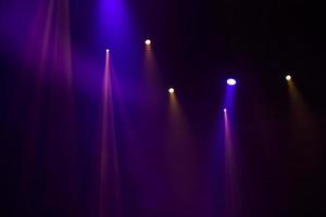 Purple beams of light from stage spotlights on a dark background. photo