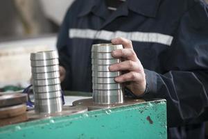 Turning shop or production. Worker's hands hold a metal product coupling. photo