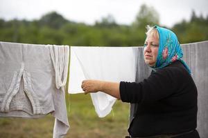 julio 20, 2022 bielorrusia, el pueblo de lyaskovichi. refugiado campamento.a mujer en un refugiado acampar cuelga ropa a seco afuera. foto